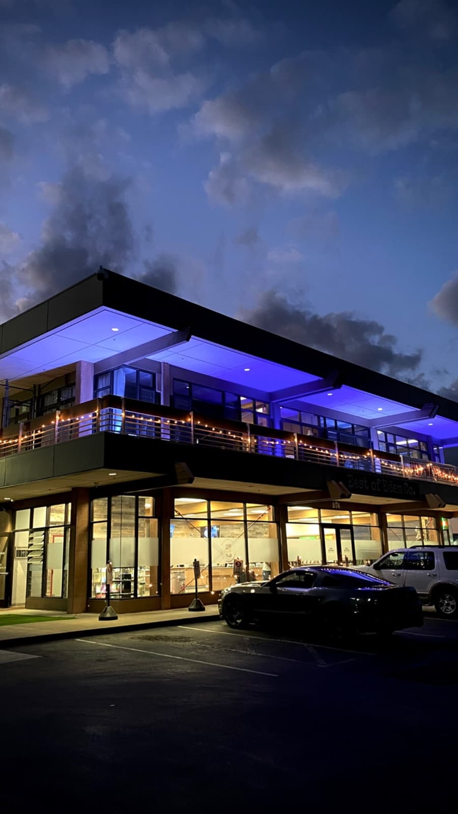 The Salinas Marketing office at 418 Work Street: the East of Eden Co. building at dusk, its balcony soffit lit blue and the storefront below it lit warm
